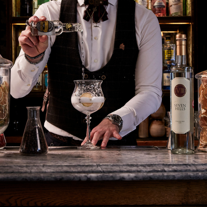 bartender pouring tonic into a gin glass