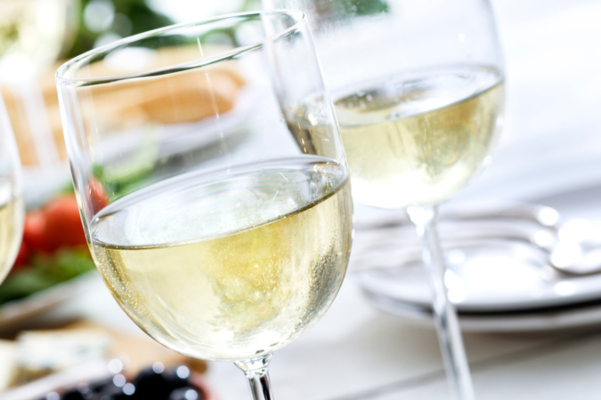 three clear wine glasses filled with white wine