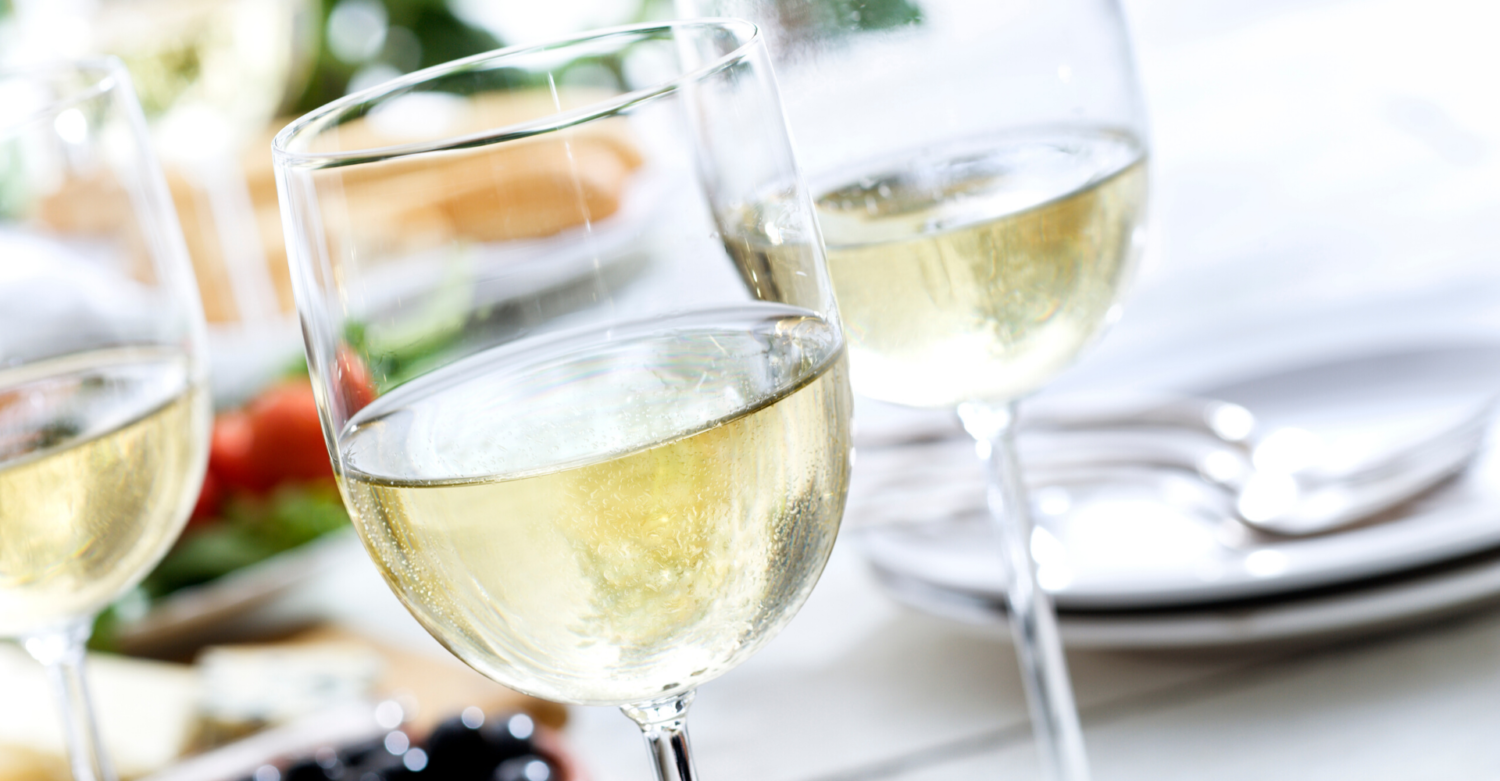 three clear wine glasses filled with white wine