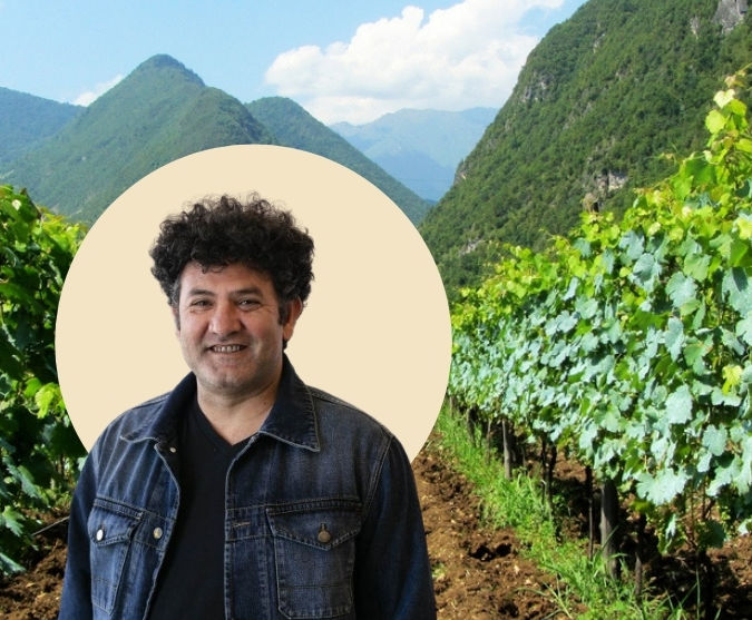Isa Bal standing in a vineyard in front of a mountain landscape.