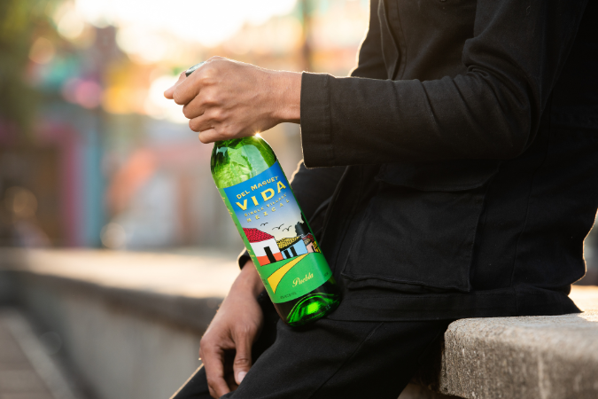 A hand holds a green bottle of Del Maguey Vida Puebla mezcal