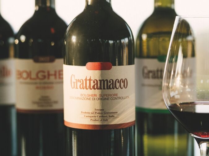 Four bottles of Grattamacco with a glass of red wine: lead image