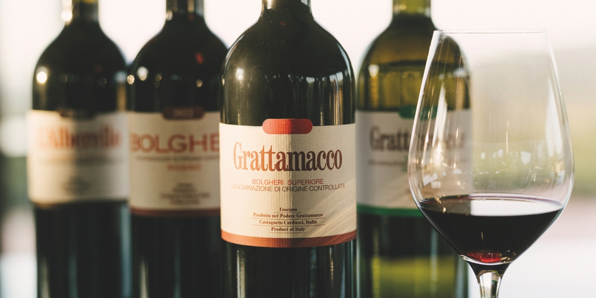 Four bottles of Grattamacco with a glass of red wine: lead image