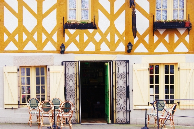 An ancient building hosts table a chairs outside. In Brittany many of the best bars and pubs are housed within its stunning historic architecture.