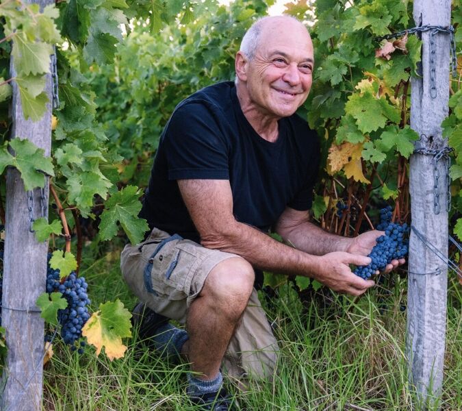 Will Berliner crouching between vines at a Cloudburst vineyard
