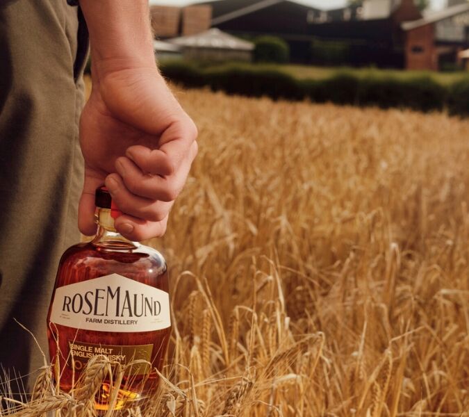 Man holding a bottle of Rosemaund whisky in a field of grain