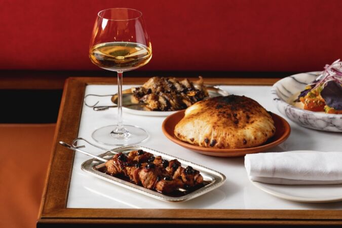 A table with various dishes and a glass of wine on it at DakaDaka restaurant