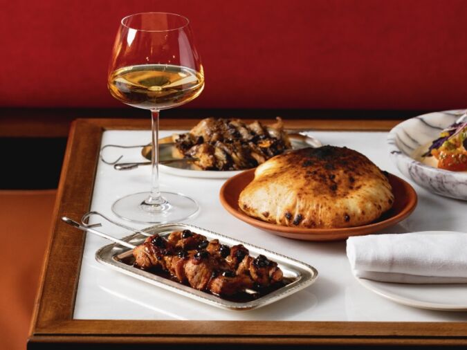 A table with various dishes and a glass of wine on it at DakaDaka restaurant