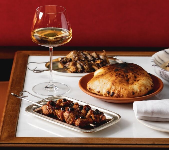 A table with various dishes and a glass of wine on it at DakaDaka restaurant