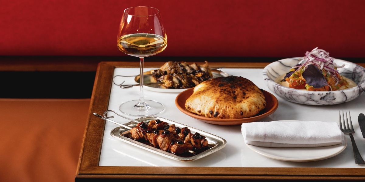 A table with various dishes and a glass of wine on it at DakaDaka restaurant