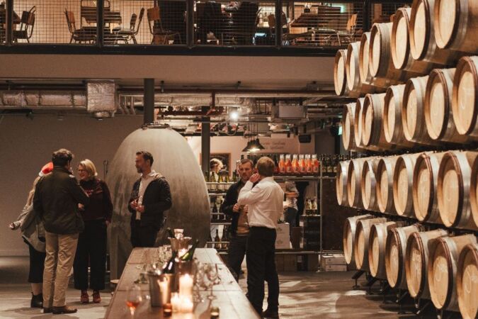 people drinking by barrels in vagabond urban winery