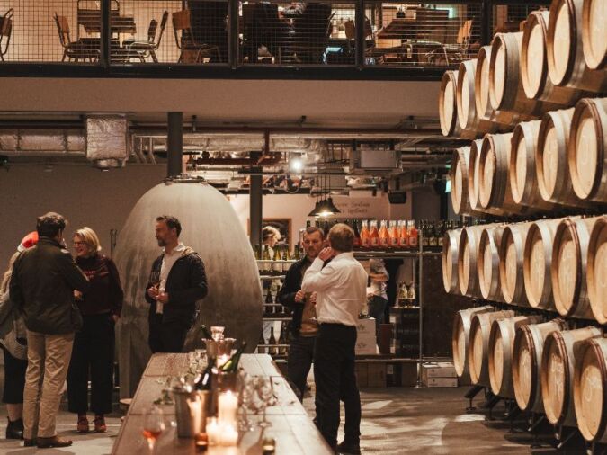 people drinking by barrels in vagabond urban winery