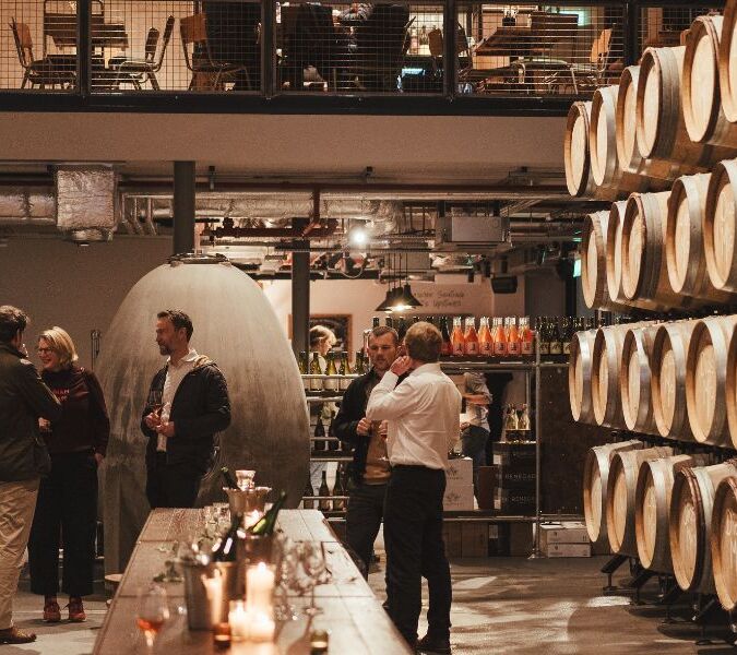 people drinking by barrels in vagabond urban winery