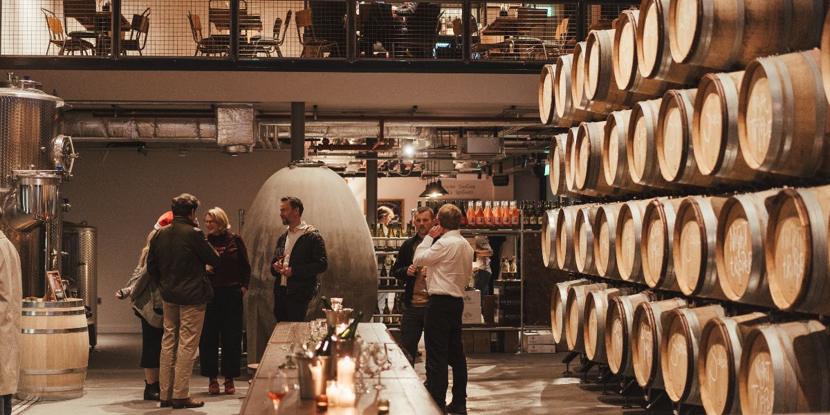 people drinking by barrels in vagabond urban winery