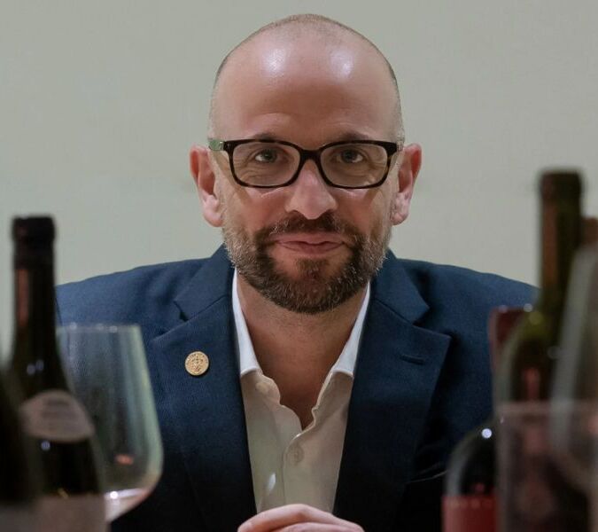 richard hemming mw surrounded by wine bottles