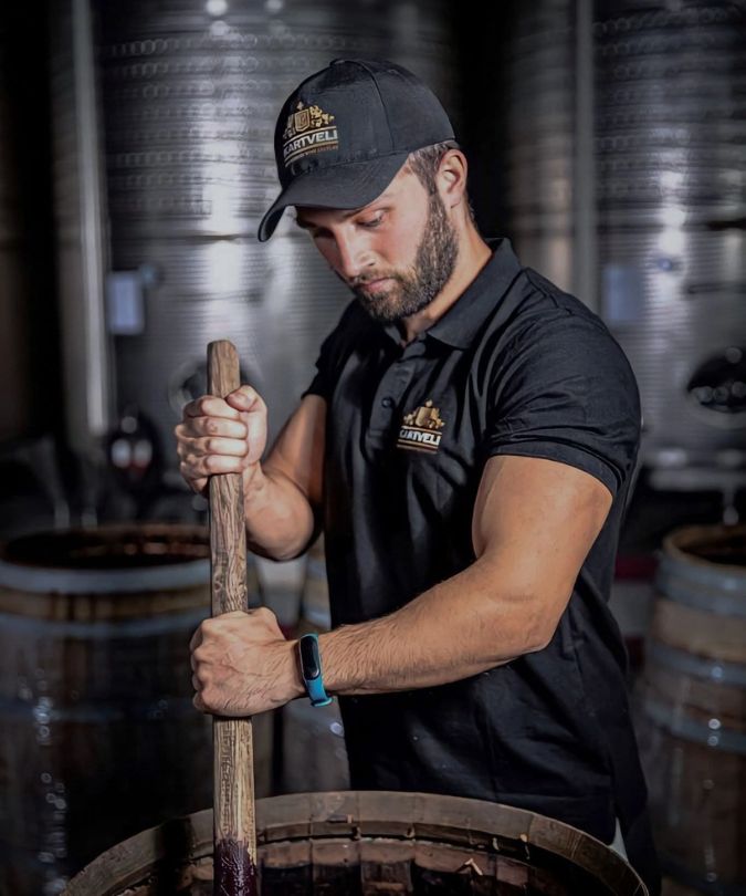 Georgian winemaker Dito Tavberidze in the Kartveli winery stirring barrel