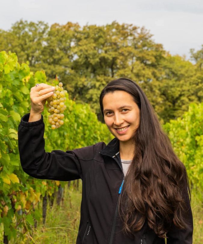 Young Georgian winemaker Sopho Khutidze holding up grapes in the vineyard